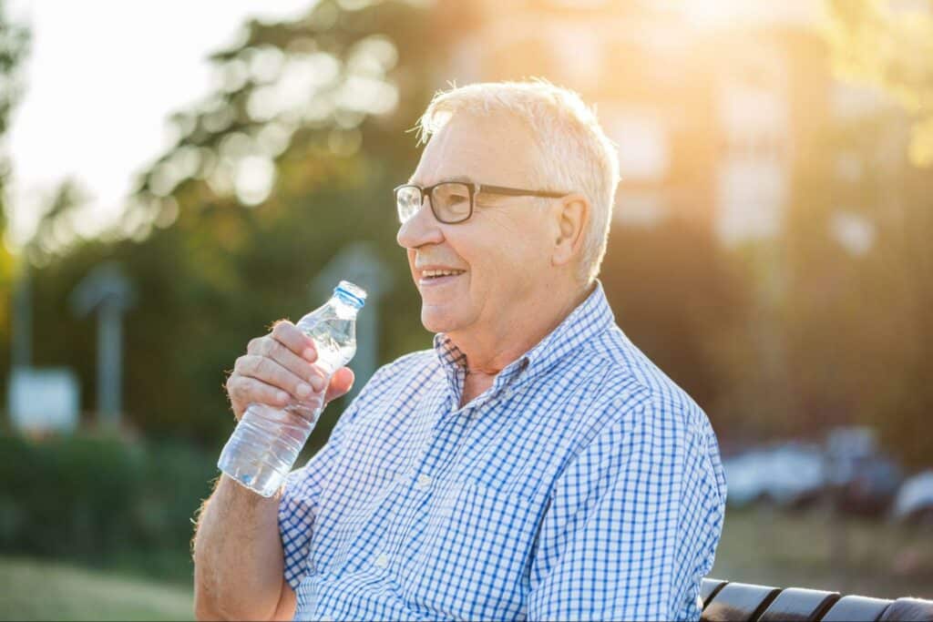 senior-man-hydrating-in-park-during-summer