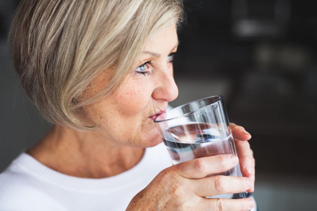 older-woman-hydrating-with-glass-of-water