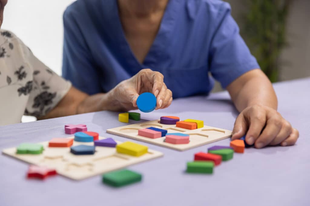 elderly-woman-doing-puzzle-in-assisted-living-with-nurse